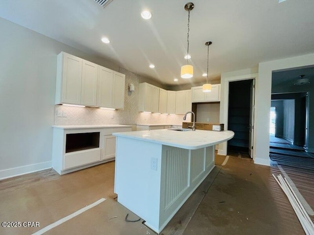 kitchen featuring white cabinetry, sink, hanging light fixtures, and a center island with sink