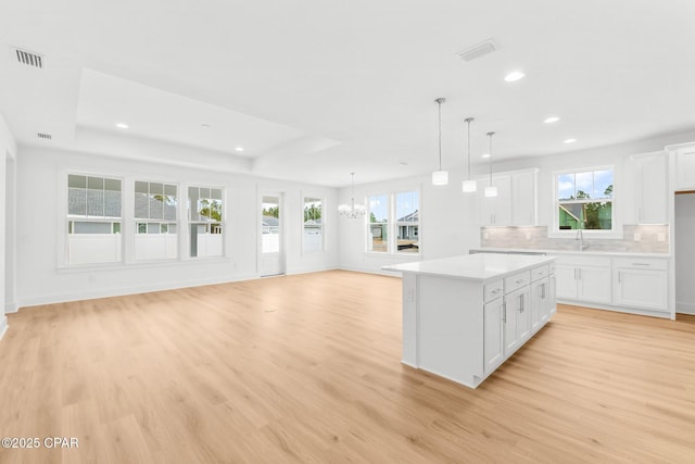 kitchen with a center island, white cabinets, light hardwood / wood-style floors, and decorative light fixtures