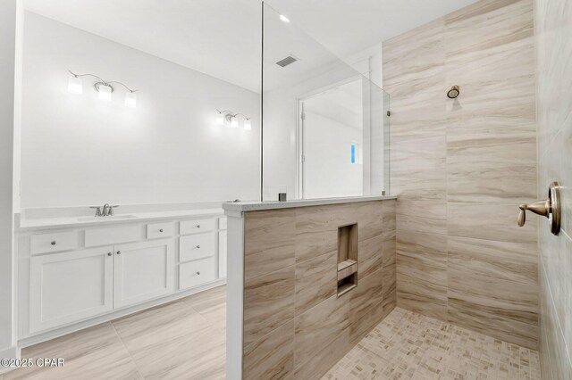 bathroom with a tile shower and vanity