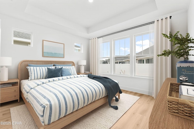 bedroom featuring a tray ceiling and light wood-type flooring