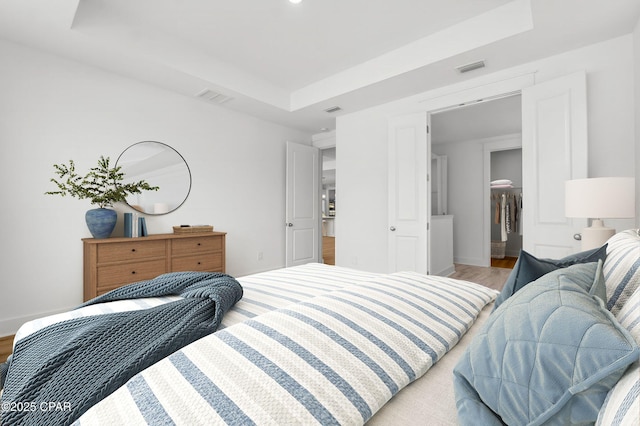 bedroom with a raised ceiling and light hardwood / wood-style flooring