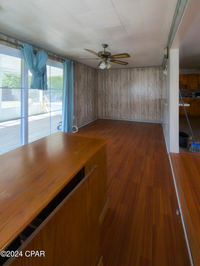 interior space featuring dark hardwood / wood-style flooring, wood walls, and ceiling fan