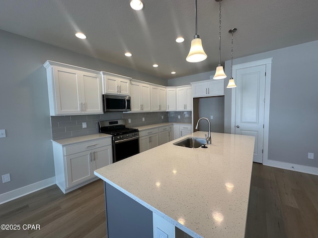 kitchen featuring pendant lighting, sink, appliances with stainless steel finishes, tasteful backsplash, and white cabinetry