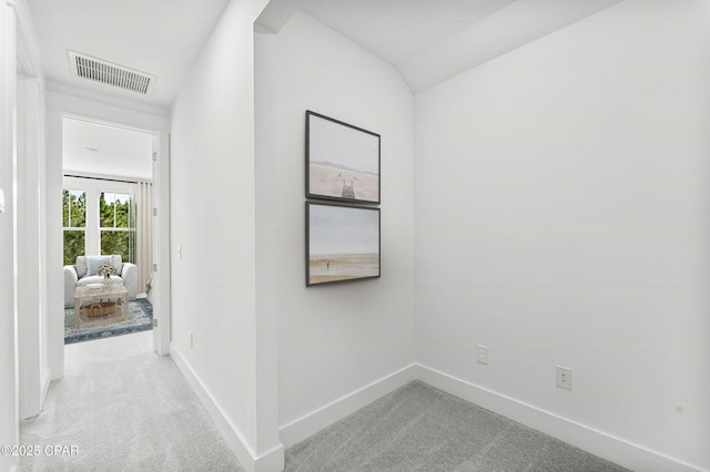 hall with lofted ceiling and light carpet