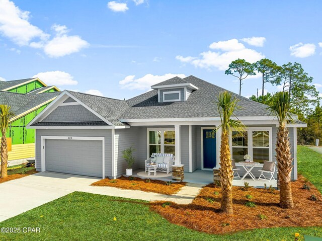 view of front of house featuring a garage, a front lawn, and covered porch