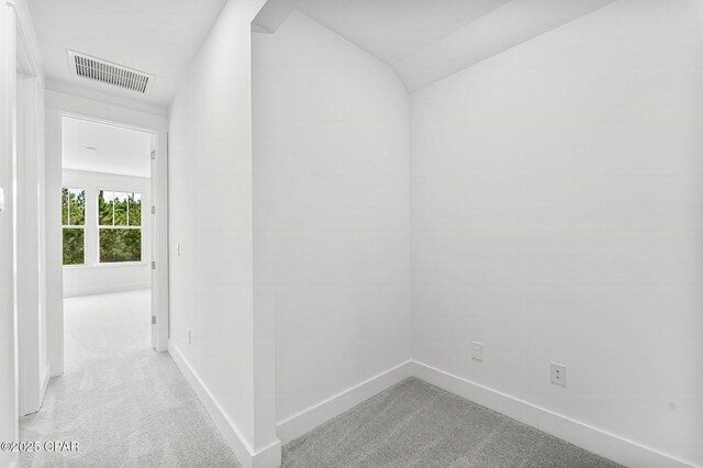 hall with lofted ceiling and light carpet