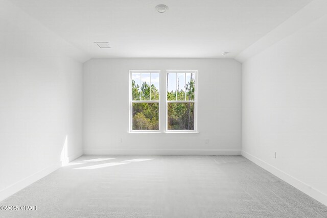 carpeted spare room with vaulted ceiling