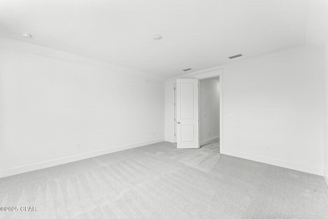 empty room with vaulted ceiling and light colored carpet