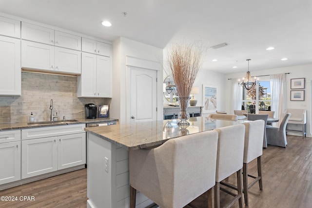 kitchen featuring a breakfast bar, sink, white cabinets, a kitchen island, and hanging light fixtures