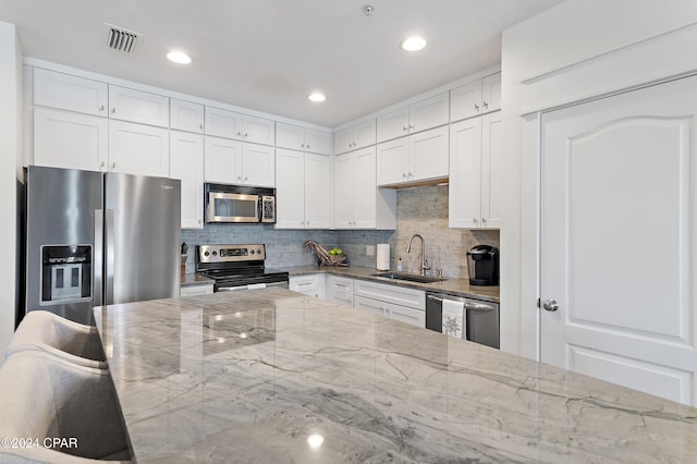 kitchen featuring light stone counters, white cabinetry, sink, and appliances with stainless steel finishes