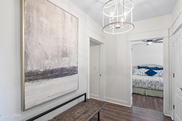 corridor with dark wood-type flooring and an inviting chandelier