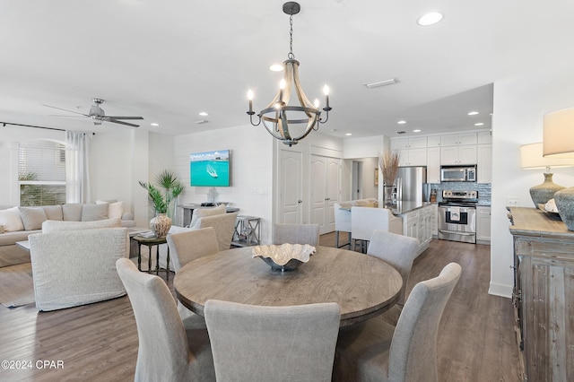 dining room featuring ceiling fan with notable chandelier and dark hardwood / wood-style flooring