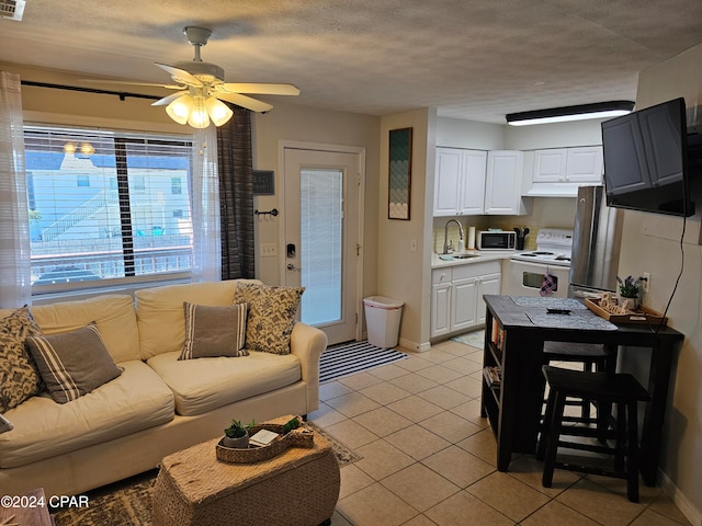 living room featuring light tile patterned floors, a textured ceiling, ceiling fan, and sink