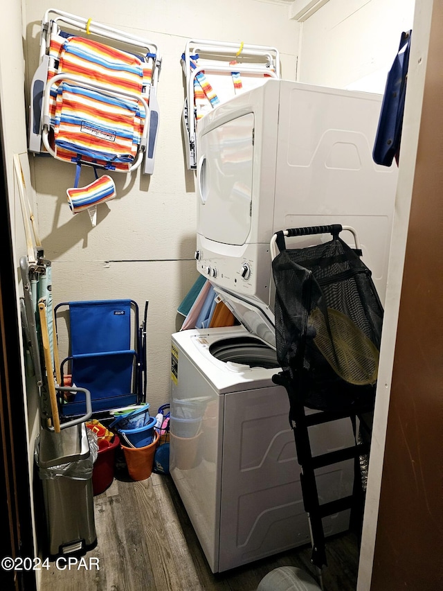 laundry area with wood-type flooring and stacked washing maching and dryer