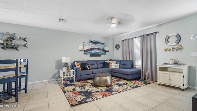 living room featuring light tile patterned floors, visible vents, a textured ceiling, and baseboards