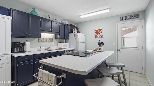 kitchen featuring white appliances, a sink, a kitchen bar, blue cabinets, and a center island