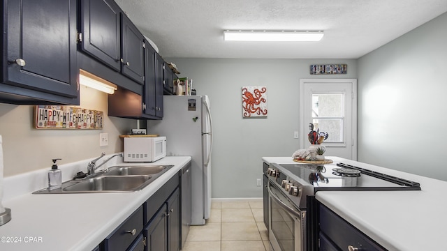 kitchen featuring a sink, a textured ceiling, stainless steel appliances, light countertops, and light tile patterned floors