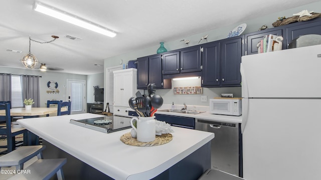 kitchen featuring visible vents, a kitchen island, a kitchen breakfast bar, white appliances, and a sink