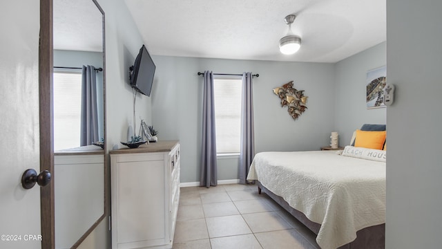 bedroom featuring light tile patterned floors, a textured ceiling, and baseboards