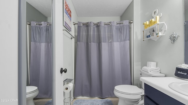 full bathroom featuring vanity, curtained shower, toilet, and a textured ceiling