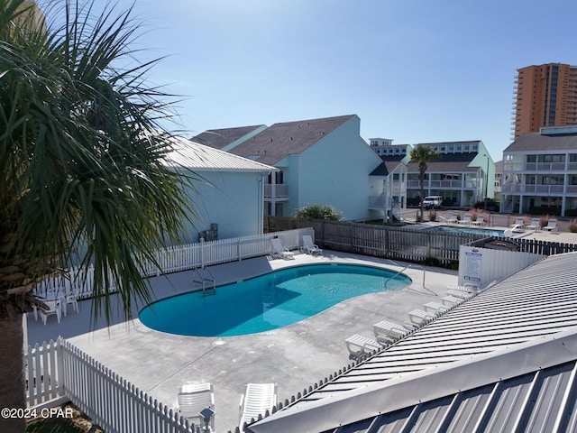 community pool with a patio area and fence