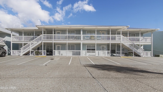 view of property featuring stairway and uncovered parking