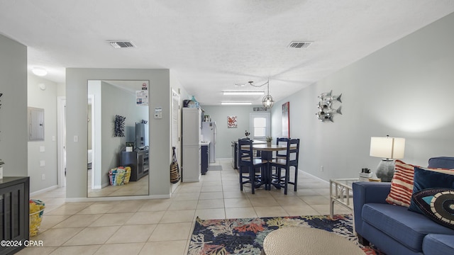 living area featuring electric panel, light tile patterned flooring, visible vents, and a textured ceiling