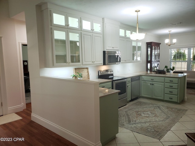 kitchen featuring kitchen peninsula, appliances with stainless steel finishes, a notable chandelier, light tile patterned flooring, and white cabinetry