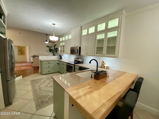 kitchen featuring pendant lighting, sink, light tile patterned floors, kitchen peninsula, and stainless steel appliances