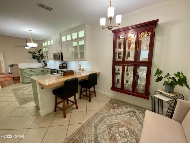 kitchen featuring kitchen peninsula, appliances with stainless steel finishes, a breakfast bar, white cabinetry, and hanging light fixtures