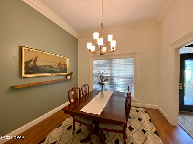 dining area with hardwood / wood-style flooring, a notable chandelier, and crown molding