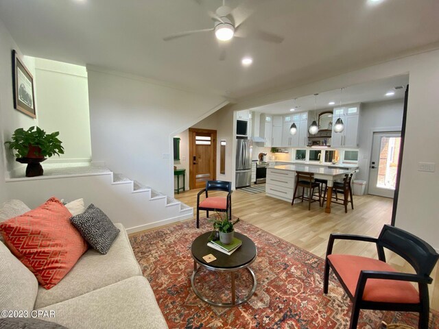 living room with ceiling fan and light hardwood / wood-style flooring