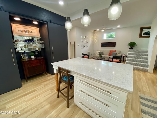 kitchen featuring ceiling fan, white cabinets, decorative light fixtures, and light wood-type flooring