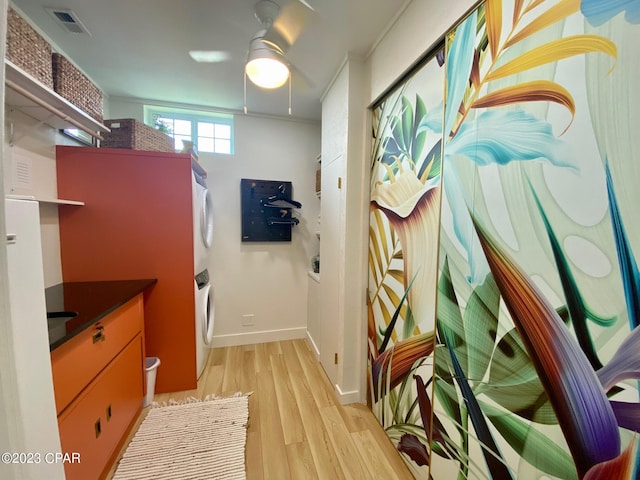 interior space featuring ornamental molding, stacked washer and clothes dryer, and light wood-type flooring