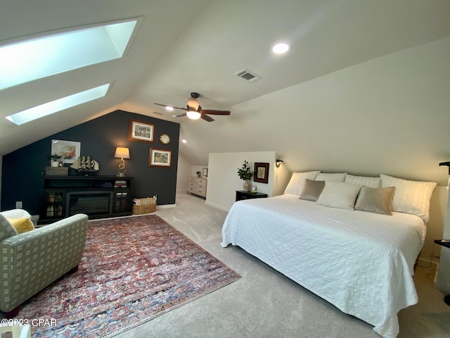 bedroom featuring vaulted ceiling with skylight, ceiling fan, and light colored carpet