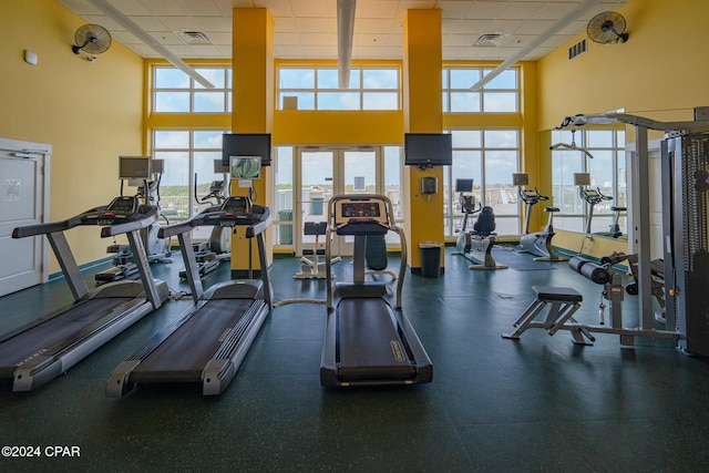 workout area featuring a drop ceiling, a towering ceiling, and plenty of natural light