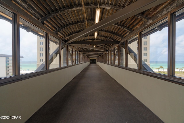 hall featuring a water view, carpet flooring, and vaulted ceiling with beams