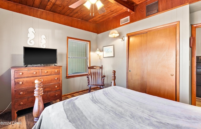 bedroom featuring dark hardwood / wood-style flooring, ceiling fan, wooden ceiling, beamed ceiling, and a closet