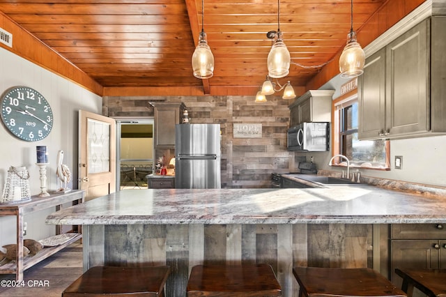 kitchen featuring a breakfast bar, hanging light fixtures, appliances with stainless steel finishes, and dark wood-type flooring