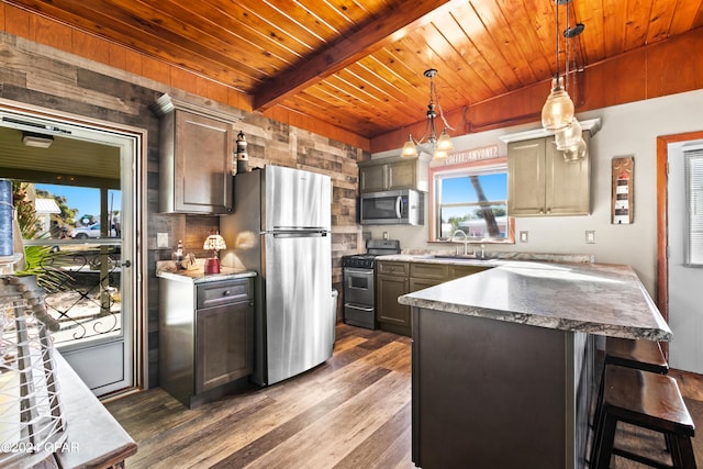 kitchen with stainless steel appliances, decorative light fixtures, a chandelier, dark hardwood / wood-style floors, and a kitchen island