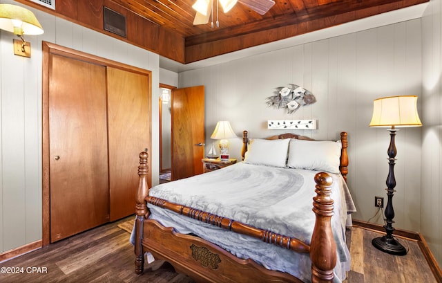 bedroom with dark hardwood / wood-style floors, a closet, wooden ceiling, and ceiling fan