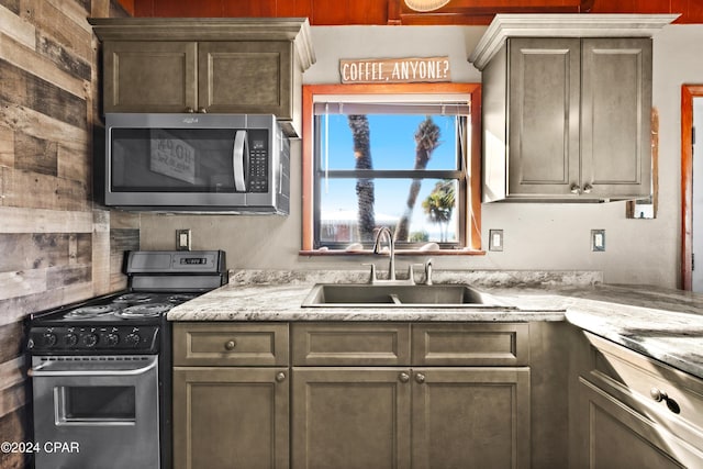 kitchen featuring light stone countertops, stainless steel appliances, and sink