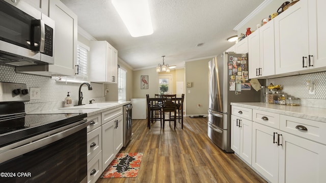 kitchen featuring white cabinetry, ornamental molding, appliances with stainless steel finishes, and sink