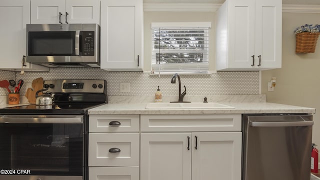 kitchen featuring sink, crown molding, white cabinetry, stainless steel appliances, and decorative backsplash