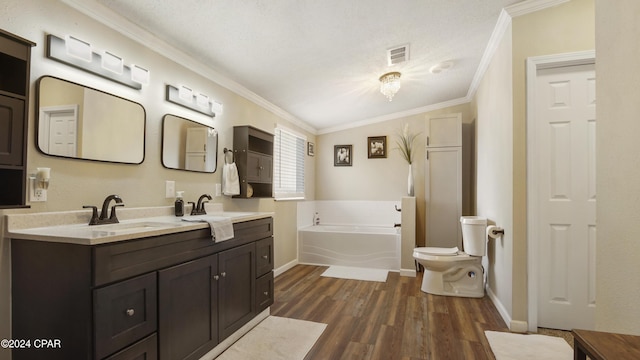 bathroom with toilet, crown molding, vanity, hardwood / wood-style flooring, and a washtub