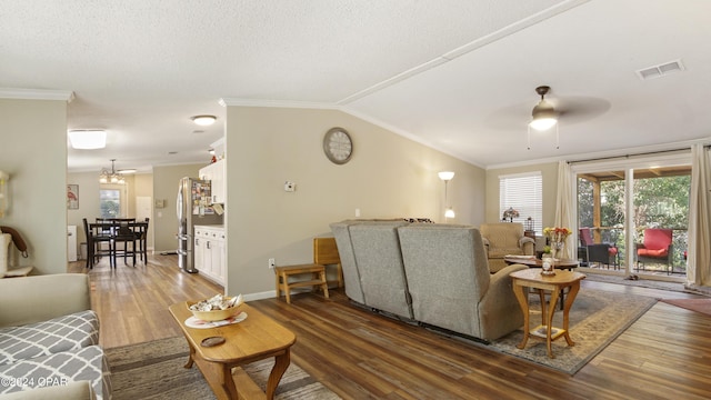 living room with vaulted ceiling, dark hardwood / wood-style floors, ceiling fan with notable chandelier, and crown molding