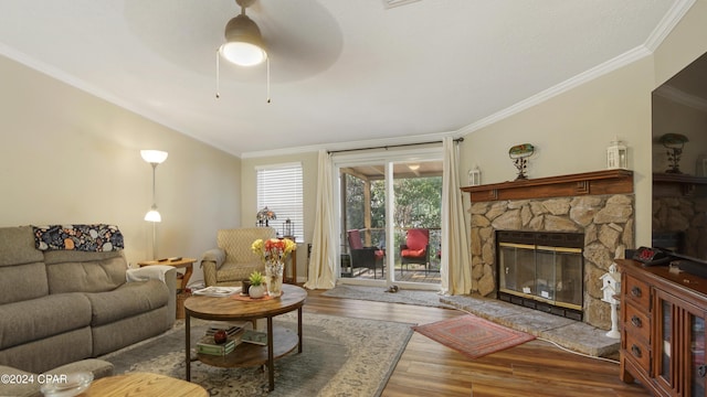 living room with vaulted ceiling, a fireplace, hardwood / wood-style flooring, ceiling fan, and crown molding