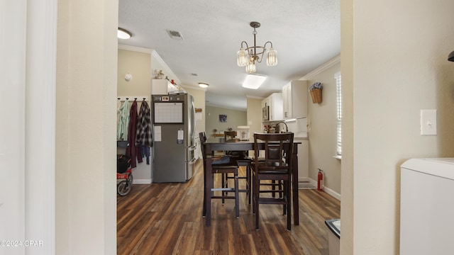 dining room featuring an inviting chandelier, washer / clothes dryer, crown molding, dark wood-type flooring, and a textured ceiling