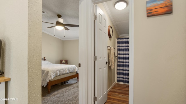 bedroom with crown molding, dark hardwood / wood-style floors, ceiling fan, and a textured ceiling