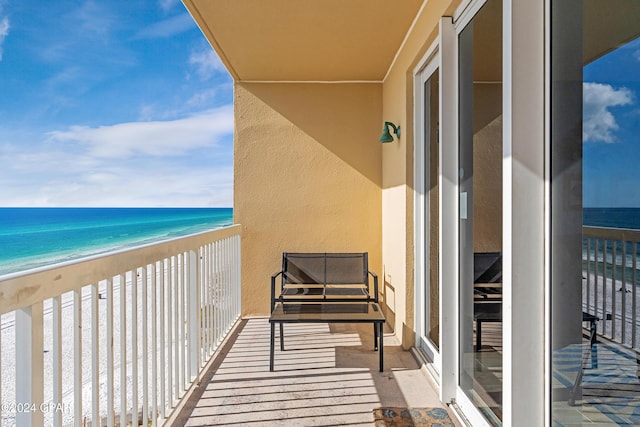 balcony with a water view and a view of the beach